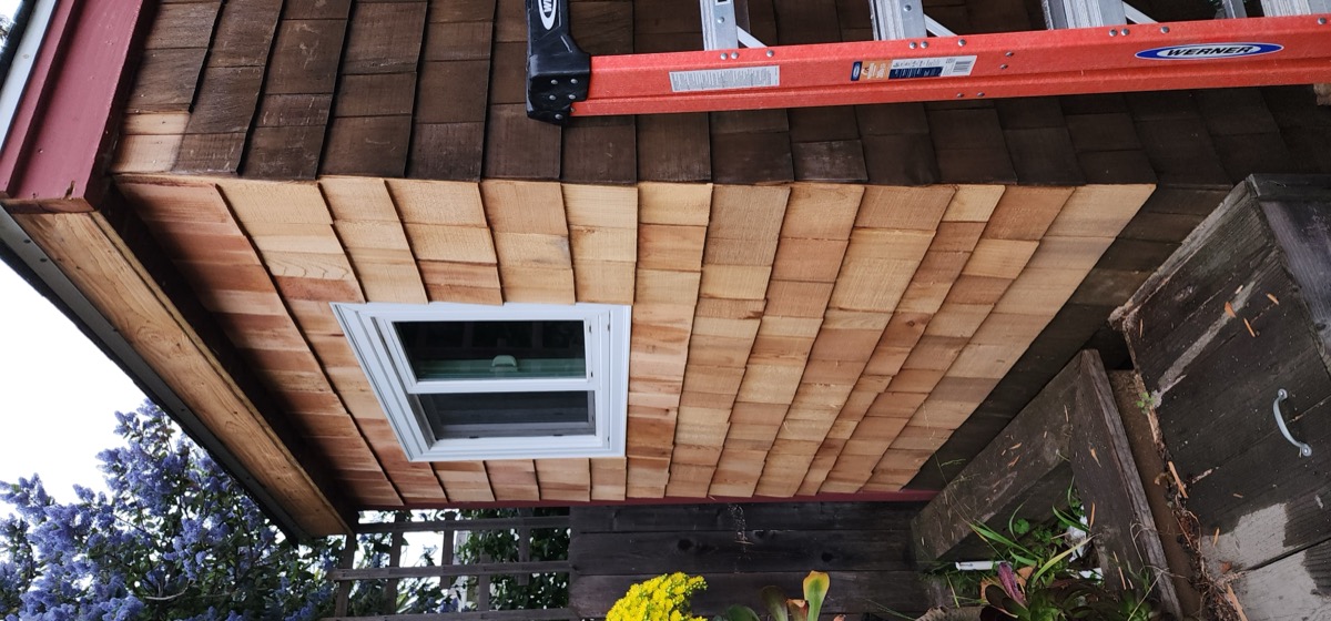 New cedar shingle siding installation with window on residential exterior